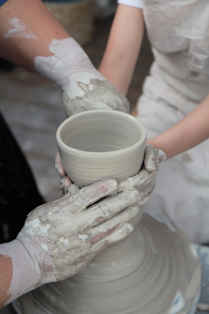 multiple people participating in clay therapy, creating a vase