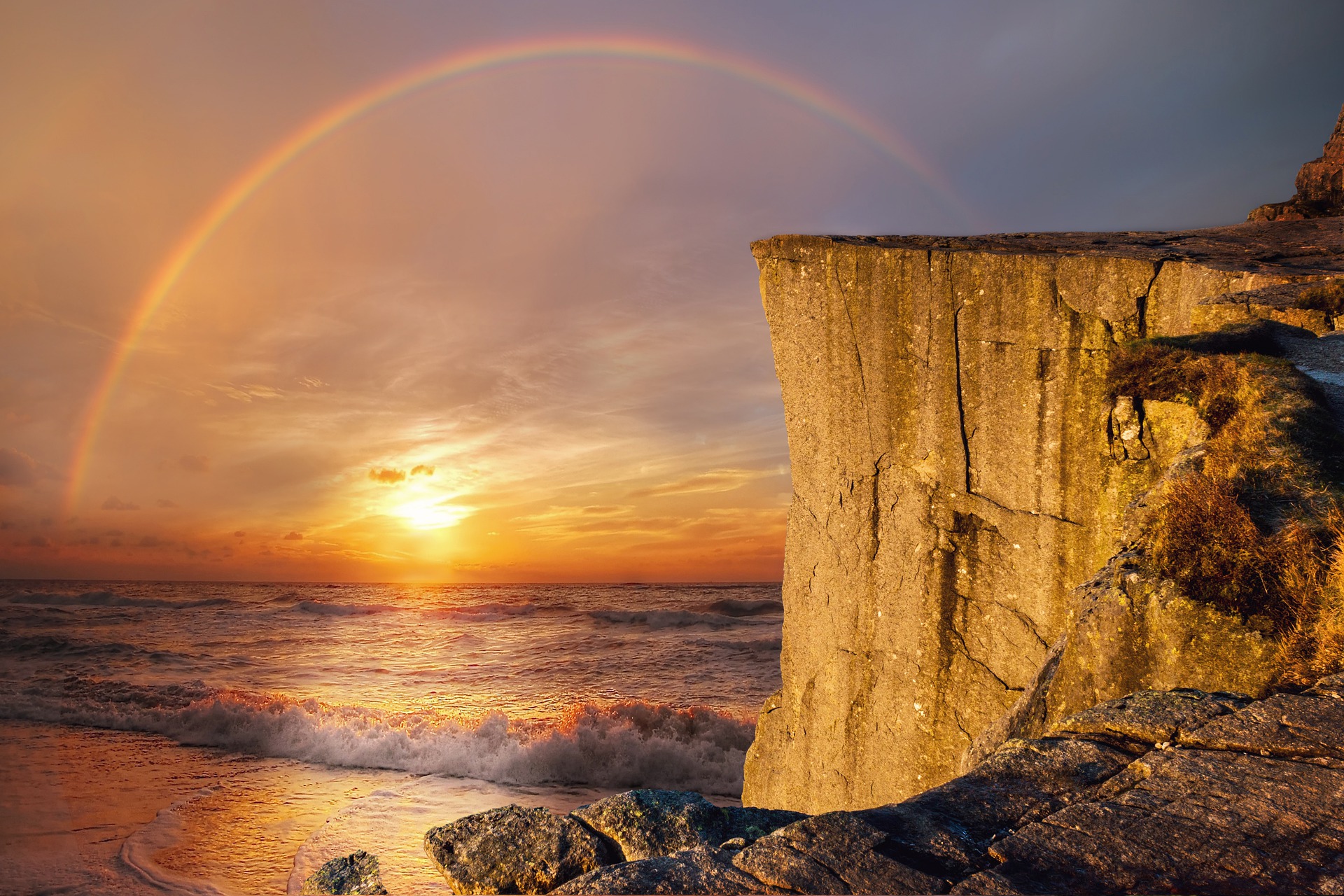 rainbow reaching over a cliff