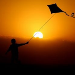 Child flying a kite at sunrise